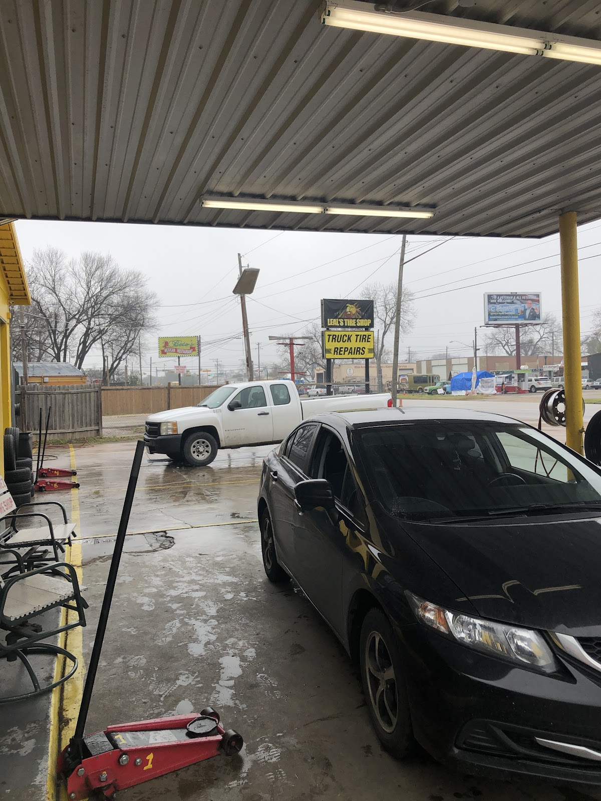Cars parked under the service canopy at Leal's Tire Shop with the pole sign in the background
