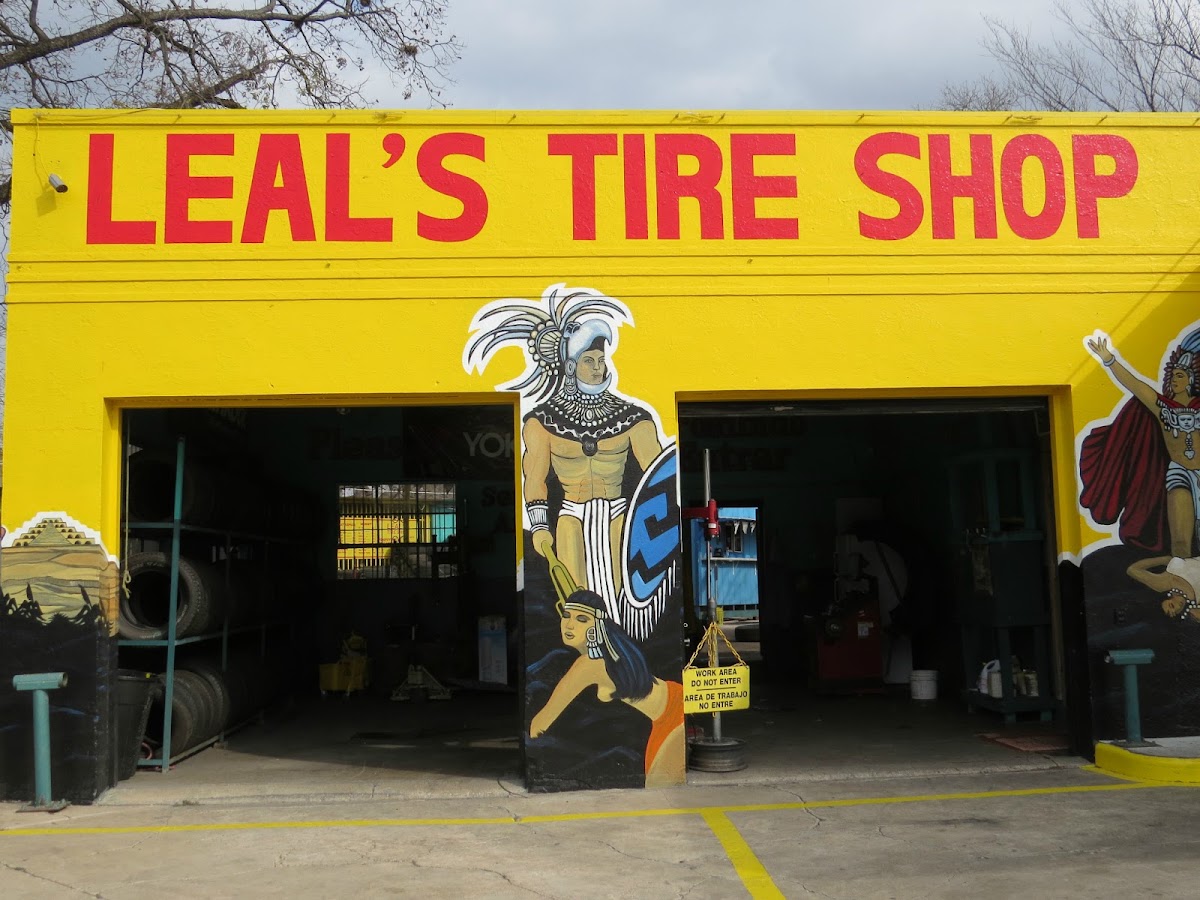 The two open garage bays at Leal's Tire Shop with a hand-painted Aztec warrior mural on the center pillar