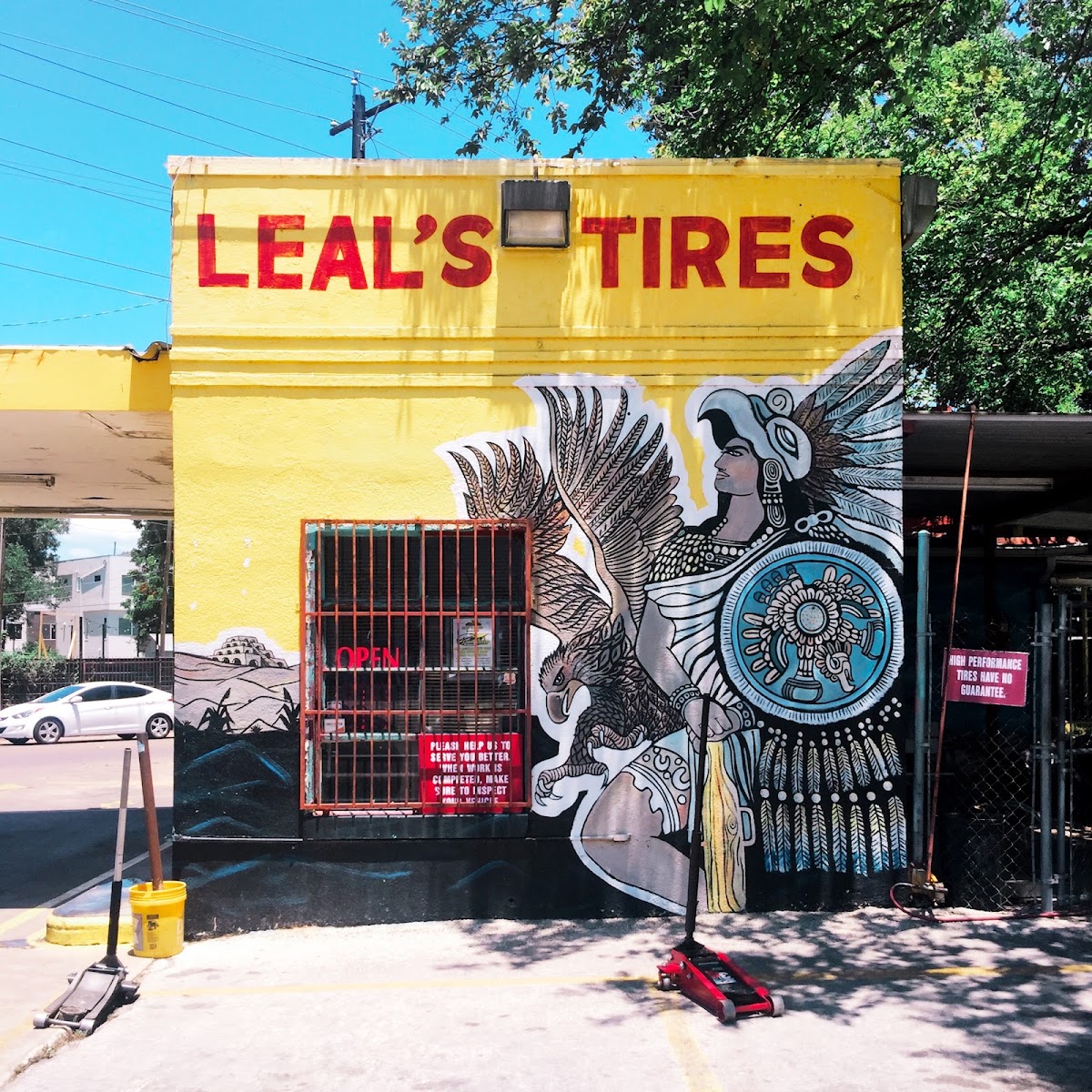 Corner of Leal's Tire Shop with the Aztec warrior mural and the OPEN sign