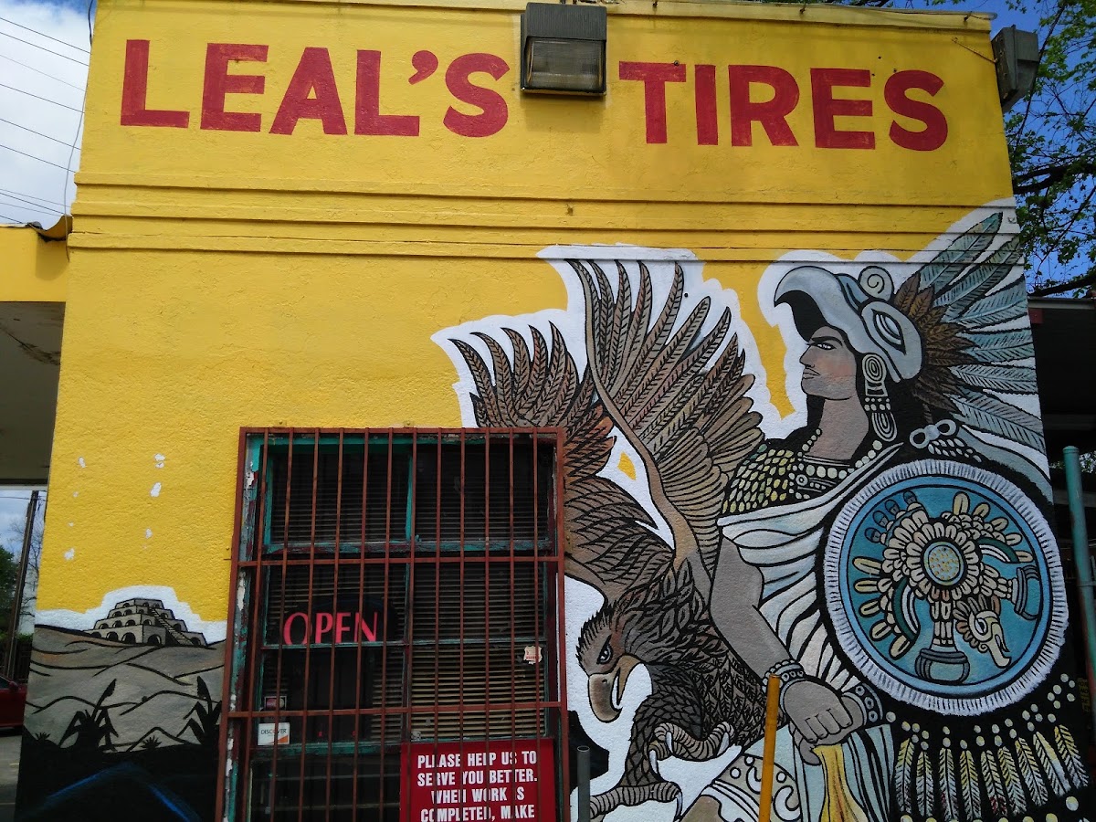 Wide shot of the Leal's Tires mural, the OPEN sign, and the storefront on E 7th Street